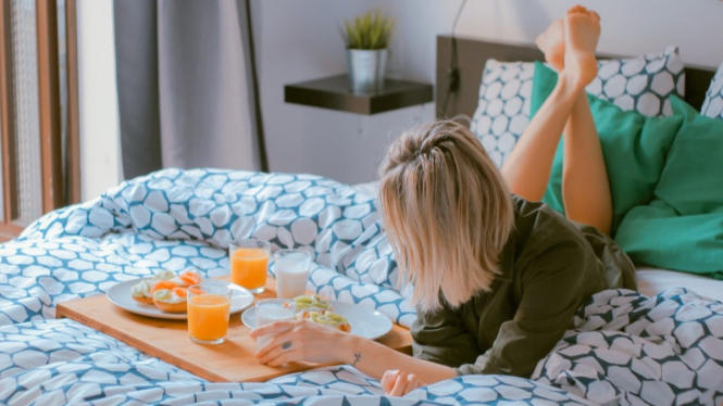 Ilustrasi seorang wanita yang self care dengan bersantai di kamar