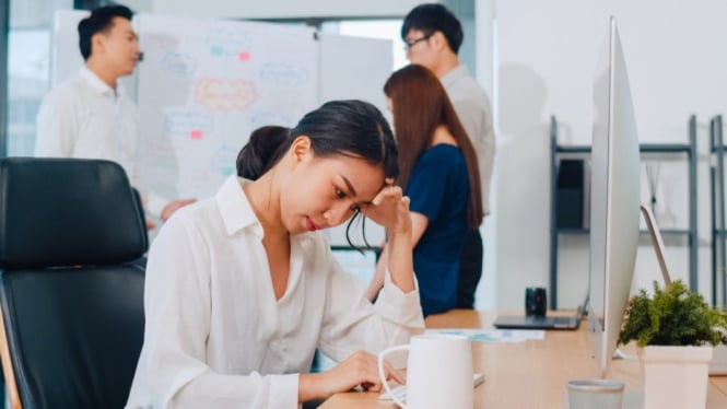 Wanita muda lelah di kantor, mencerminkan fenomena Gen Z resign.