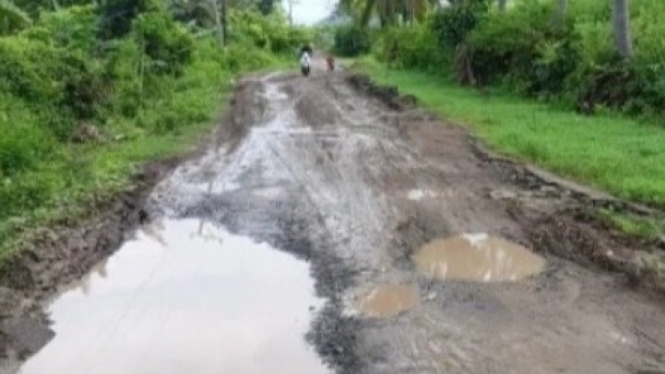 Kondisi jalan berlubang dipenuhi genangan air dan lumpur