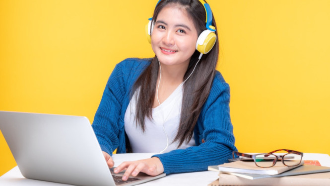 Seorang wanita belajar di meja dengan laptop