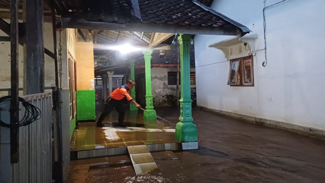 Petugas BPBD membersihkan endapan luapan air dari rumah warga