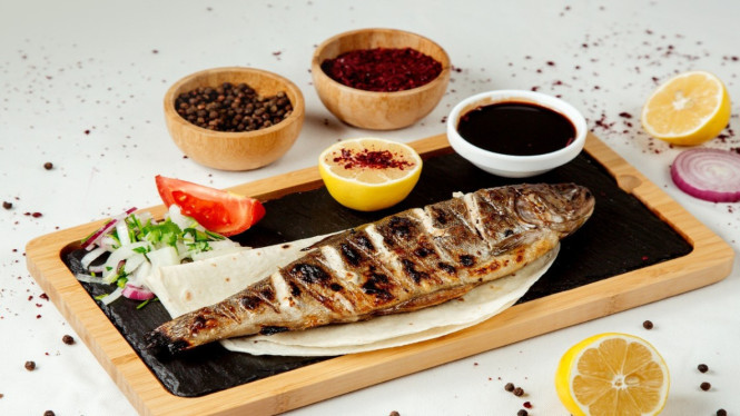 Sepiring ikan panggang madu disajikan dengan lemon