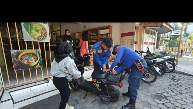 Petugas berupaya membuka jok sepeda listrik