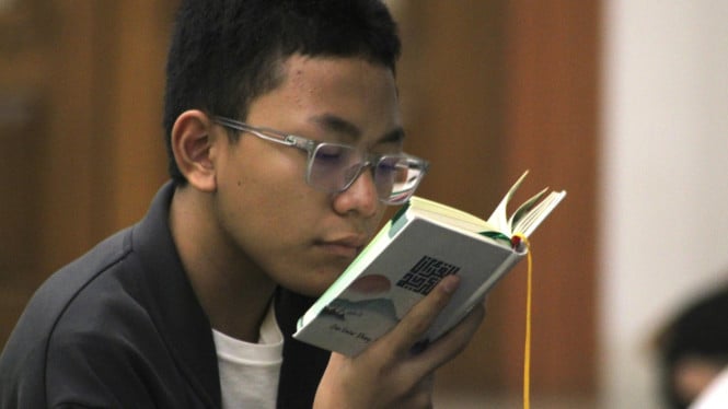 Tadarus Al-Quran oleh seorang anak saat I'tikaf di Masjid Al Hikmah