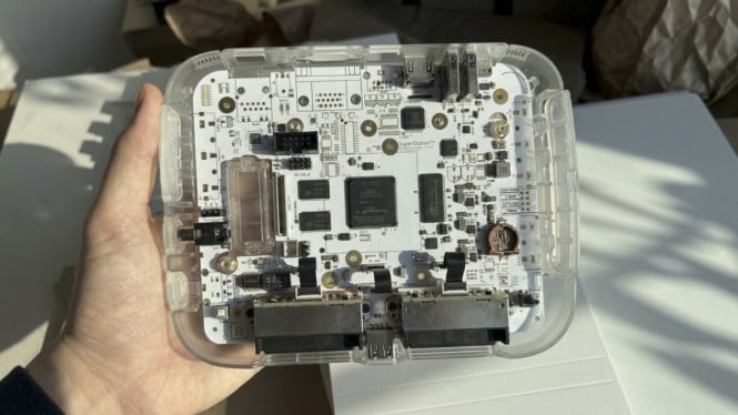 Prototipe SuperStation One Lite dengan bodi transparan memamerkan papan sirkuit internal tanpa port analog.
