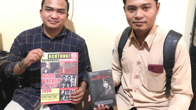 Man'uth dan Farel memegang koran Achtung dan buku hitam Prabowo