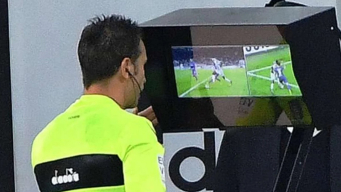 Seorang wasit menggunakan teknologi Video Assistant Referee (VAR)