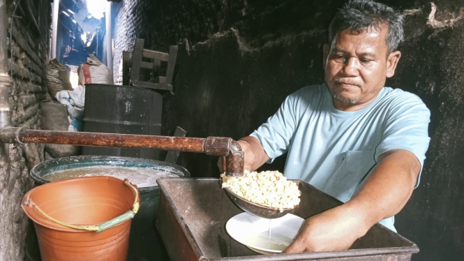 Perajin tempe Sidiq saat memproduksi tempe.