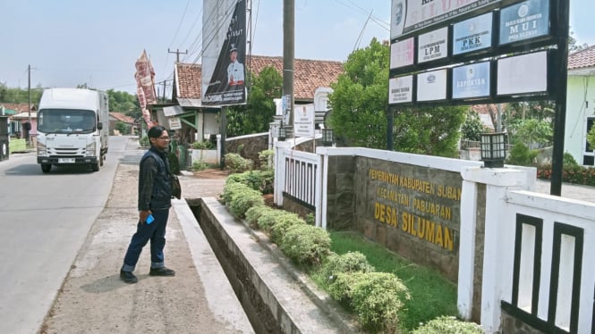 Warga saat berjalan melintasi kantor Desa Siluman