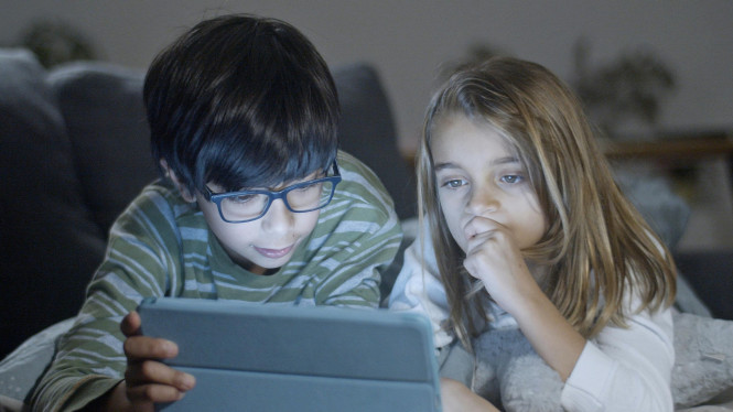 Dua anak sedang bermain tablet