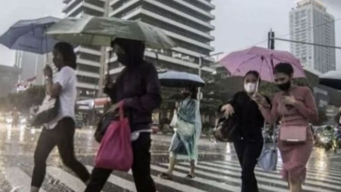 Warga Jakarta pakai payung saat hujan.