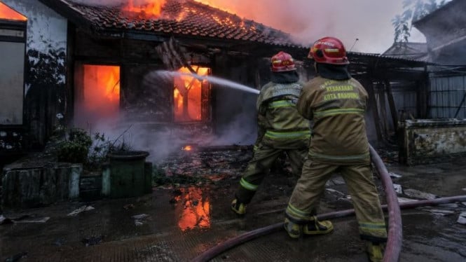 Ilustrasi petugas pemadam kebakaran padamkan rumah terbakar.
