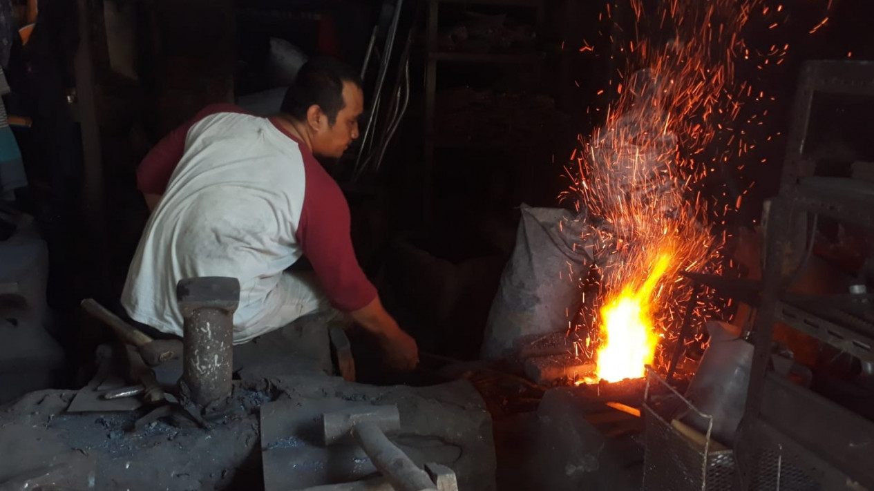 Imam Basori, sedang memanggang besi di atas tungku