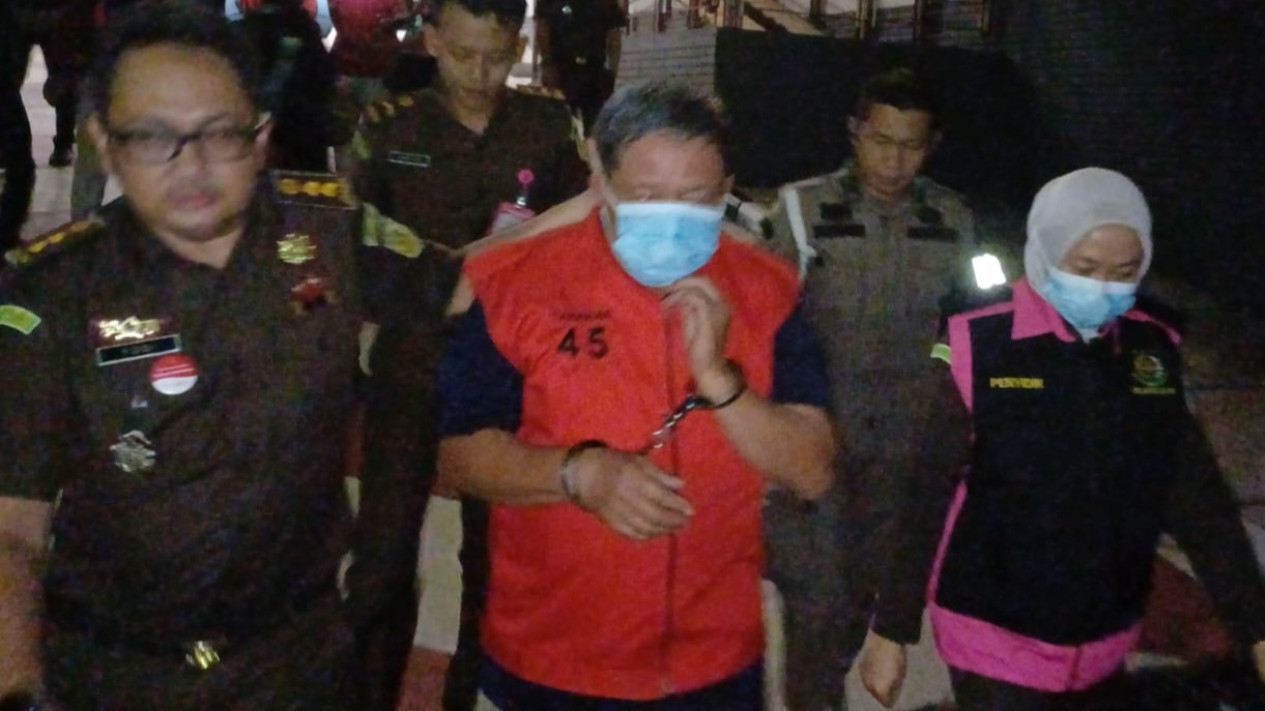 Tersangka mengenakan rompi merah.