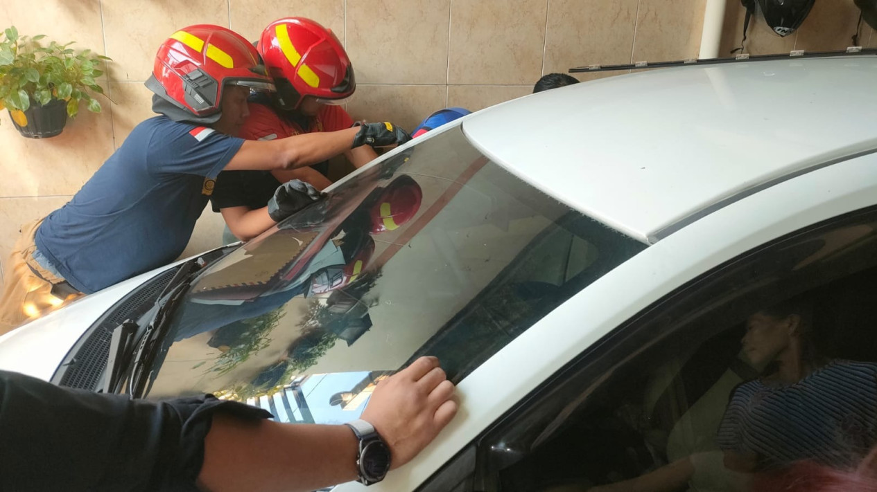 Petugas Damkar Membuka Paksa Kaca Mobil