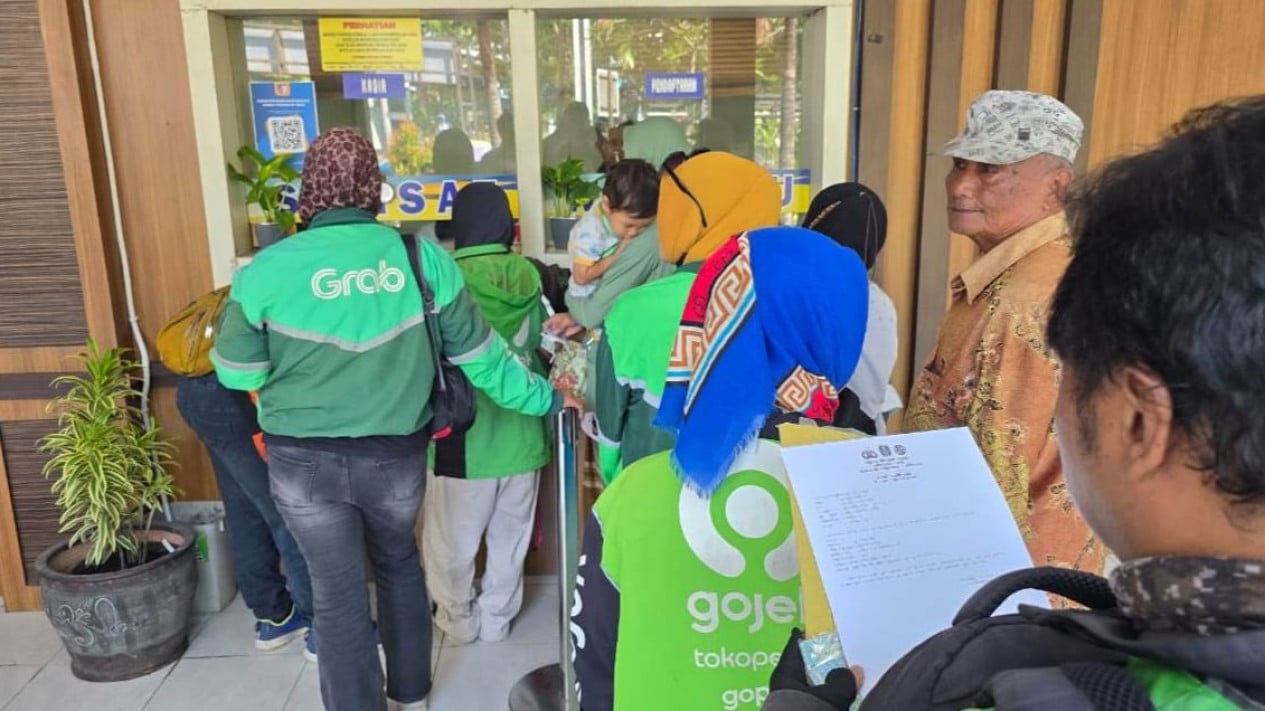 Tukang ojek online mengurus pajak kendaraan di Surabaya.