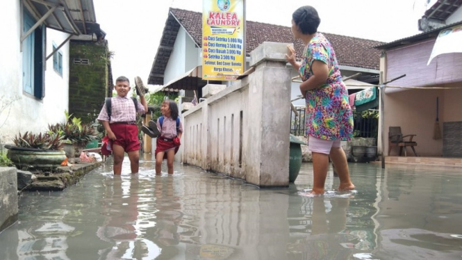 Siswa saat melintasi banjir bercampur limbah PG Mojopanggung