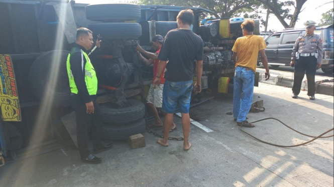 Petugas saat mengevakuasi truk yang terguling di jalan raya Nasional Babat-Lamongan