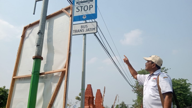 Kepala Desa Dapet Balongpanggang, Siswadi saat menunjukkan rambu stop bis Trans Jatim