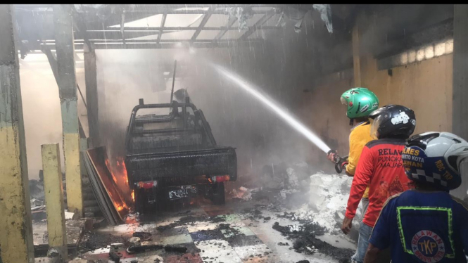 Relawan berusaha memadamkan gudang toko material di Mojokerto yang terbakar