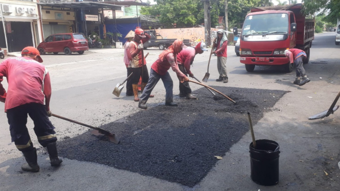 Para pekerja dari Dinas Sumber Daya Air dan Bina Marga Pemerintah Kota Surabaya sedang menambal lubang jalan.
