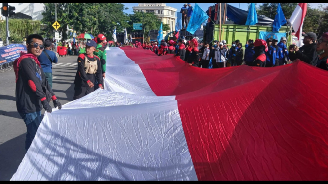 Massa buruh membentangkan bendera merah putih 100 meter saat aksi May Day di Surabaya