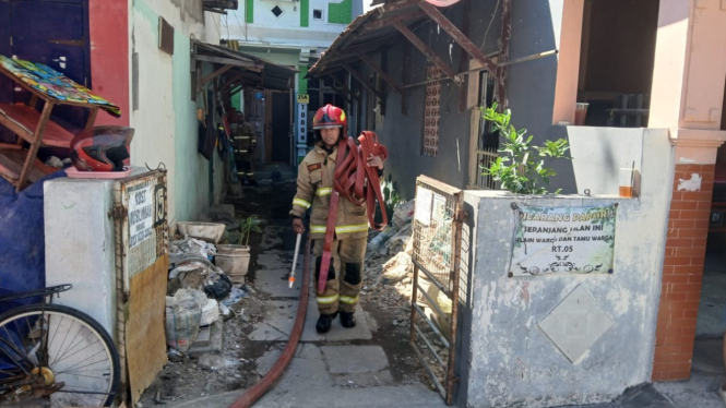 Petugas pemadam usai proses pembasahan kosan di Karangmenjangan, Surabaya yang mengalami kebakaran