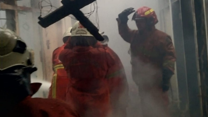 Petugas memadamkan api di rumah terbakar di Wonokromo.