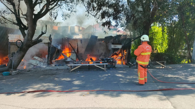 Petugas pemadam kebakaran memadamkan api di warung dan bengkel di Sukolilo Surabaya