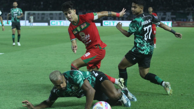 Pemain Persebaya adu skil dengan pemain PSS Sleman.