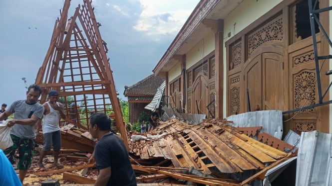 Warga membersihkan puing bangunan rumah yang ambruk