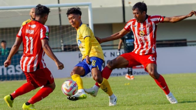 Pemain Gresik United (kuning) di hadang dua pemain Deltras Sidoarjo