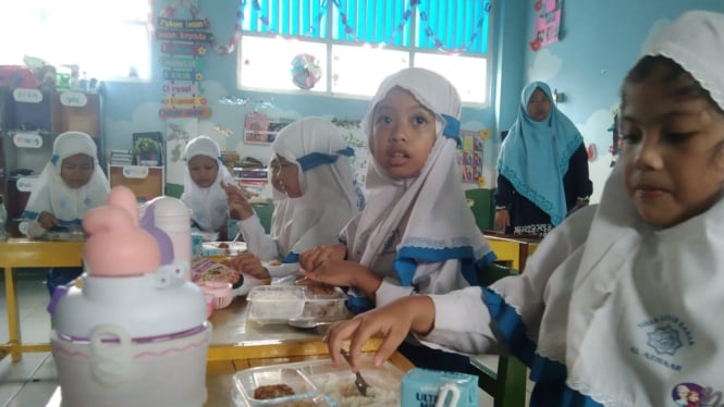 Anak-anak sedang menyantap makanan Program MBG.