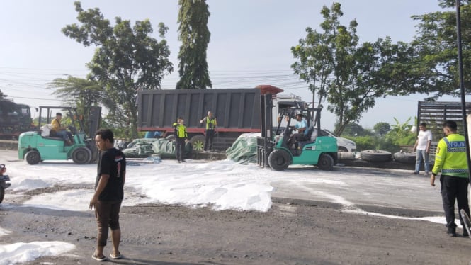 Petugas saat membersihkan gula pasir yang terguling