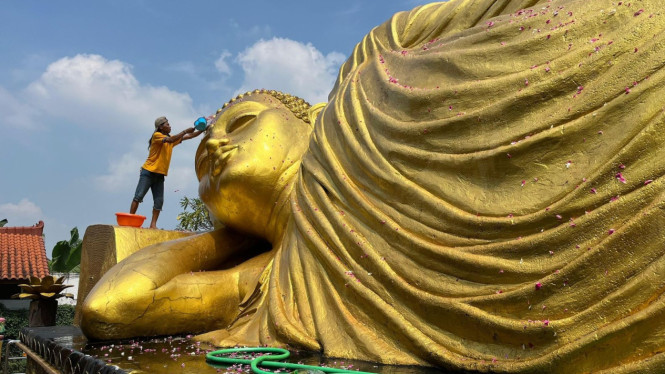Proses memandikan patung Buddha tidur.