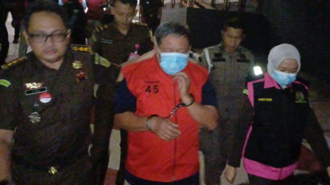 Tersangka mengenakan rompi merah.