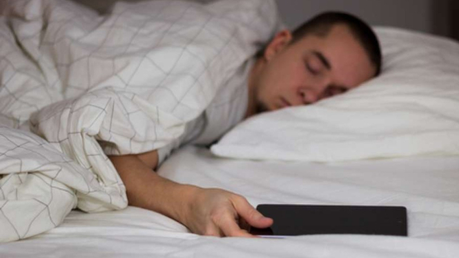 Ilustrasi tidur dekat ponsel.