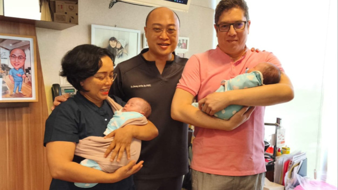 Orang tua bayi kembar identik menggendong anaknya