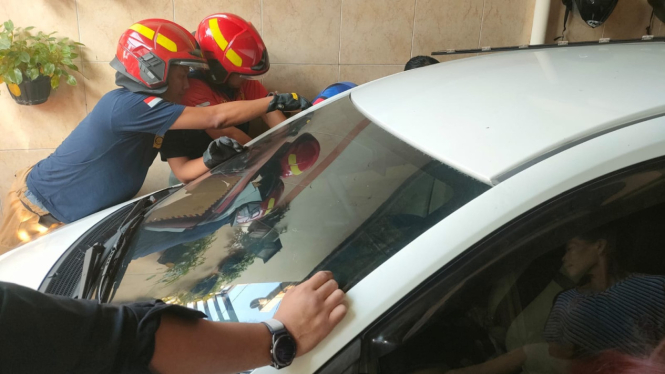 Petugas Damkar Membuka Paksa Kaca Mobil