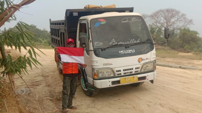 Pengemudi truk menunjukkan bendera merah putih yang diberi warga.