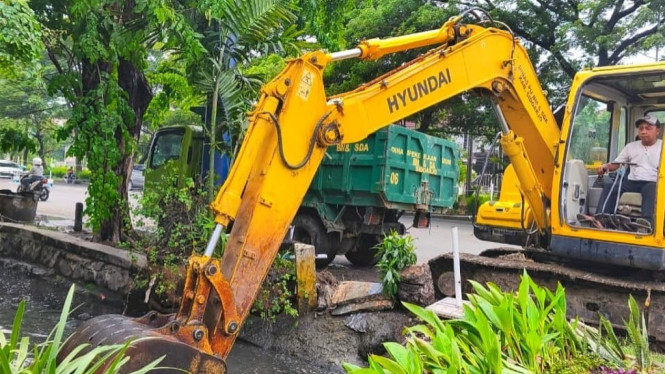 Pekerja mengeruk sungai di sekitar jalan depan Lippo Plaza Sidoarjo.