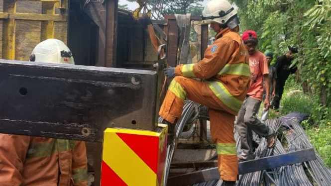 Petugas mengangkat truk terguling.