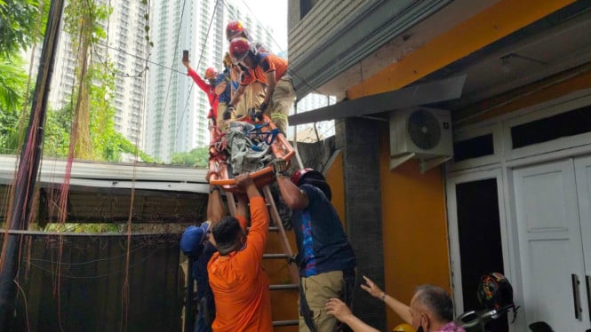 Petugas mengevakuasi lansia yang tertidur di atap rumah.