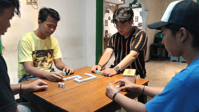 Empat orang sedang bermain domino.
