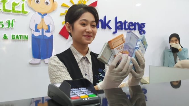 Teller Bank Jateng Kudus menunjukan lembaran uang baru