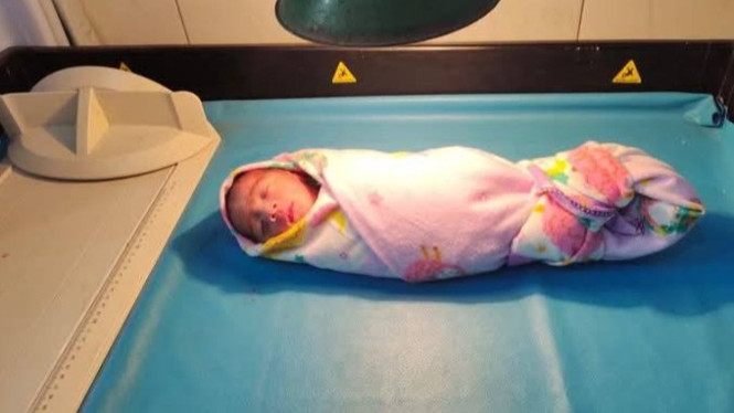 Tubuh bayi hanya dibungkus sarung bantal berwarna pink.