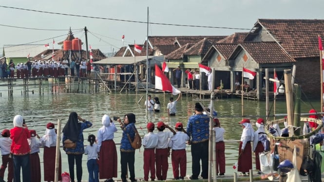 Warga Timbulsloko, Kecamatan Sayung, Kabupaten Demak upacara bendera HUT ke 81 RI di tengah rob
