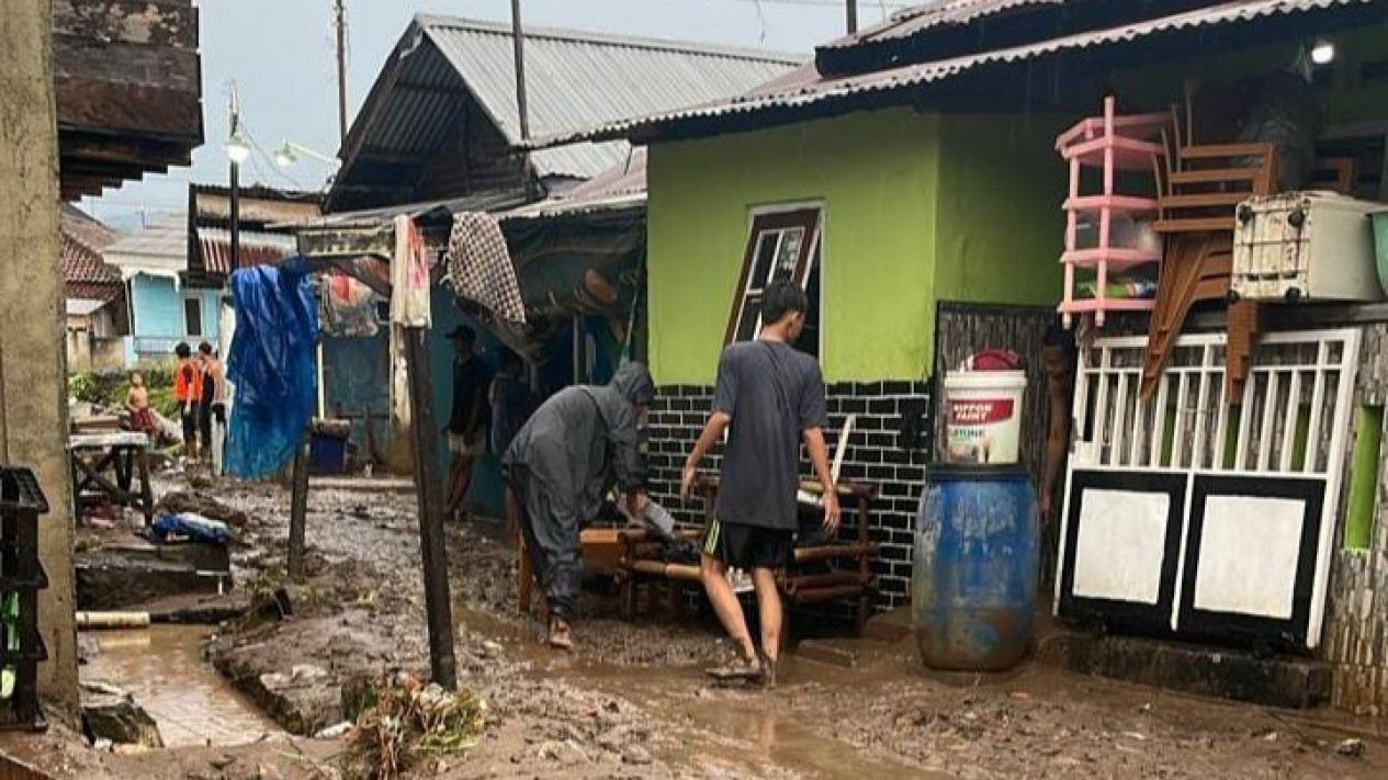Warga tampak membersihkan lumpur sisa banjir
