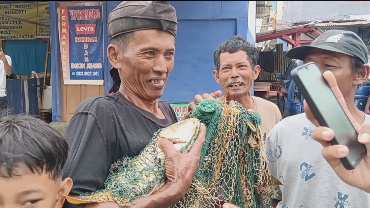 Slamet saat dapat ikan mas hasil jaring di lokasi banjir