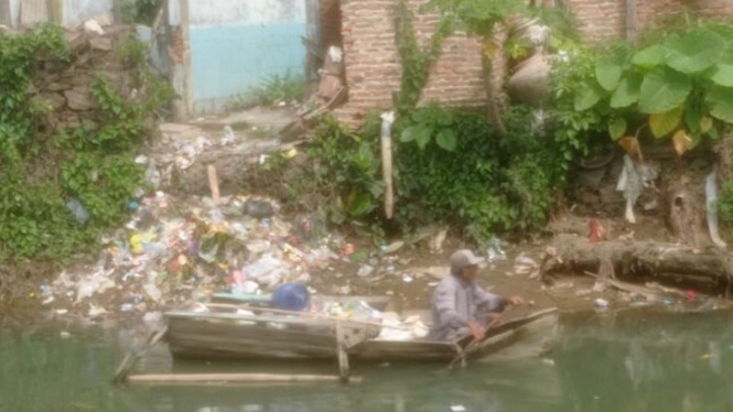Seorang warga sedang mengumpulkan sampah di sungai Way Belau